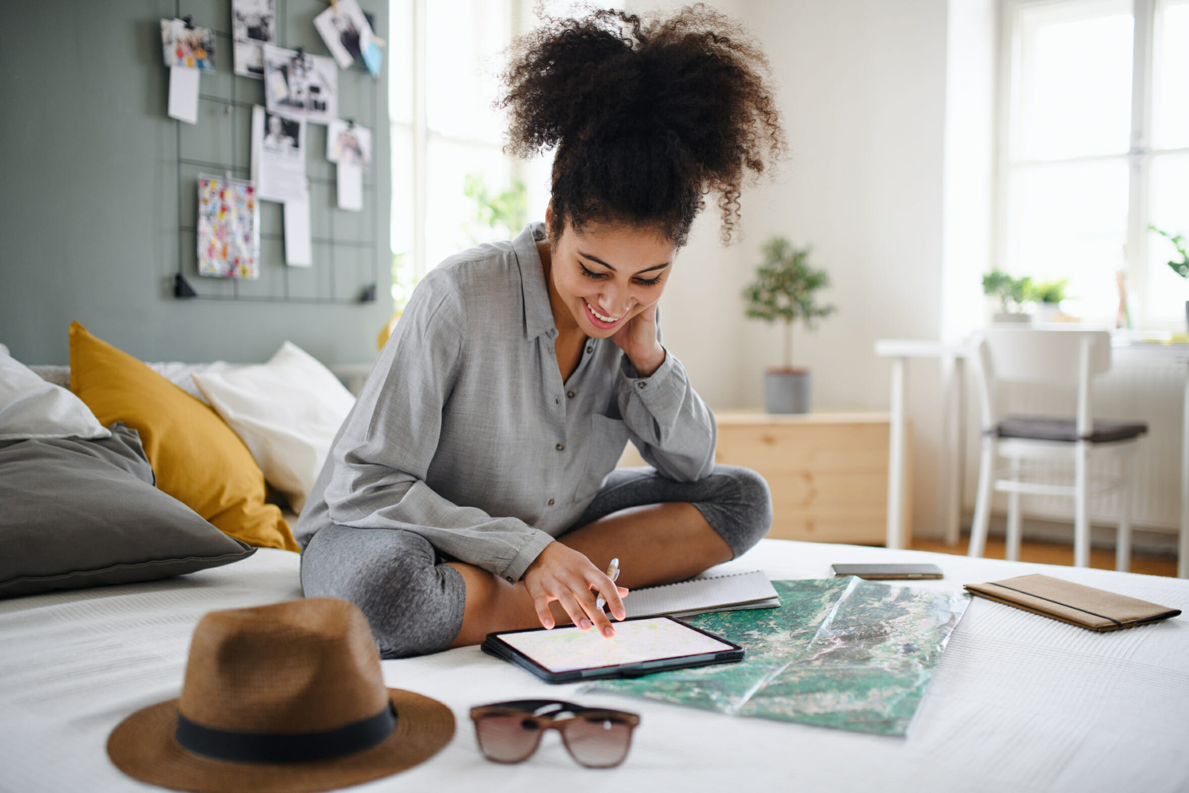 Young woman with tablet and map indoors at home, planning traveling trip