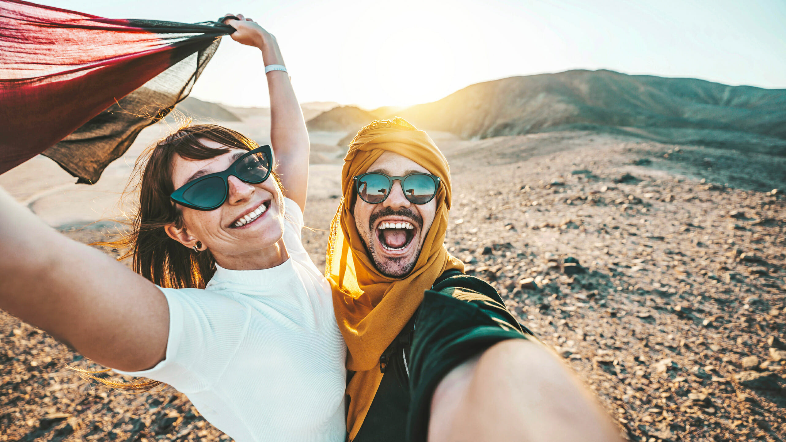 Happy couple of travelers taking selfie picture in rocky desert