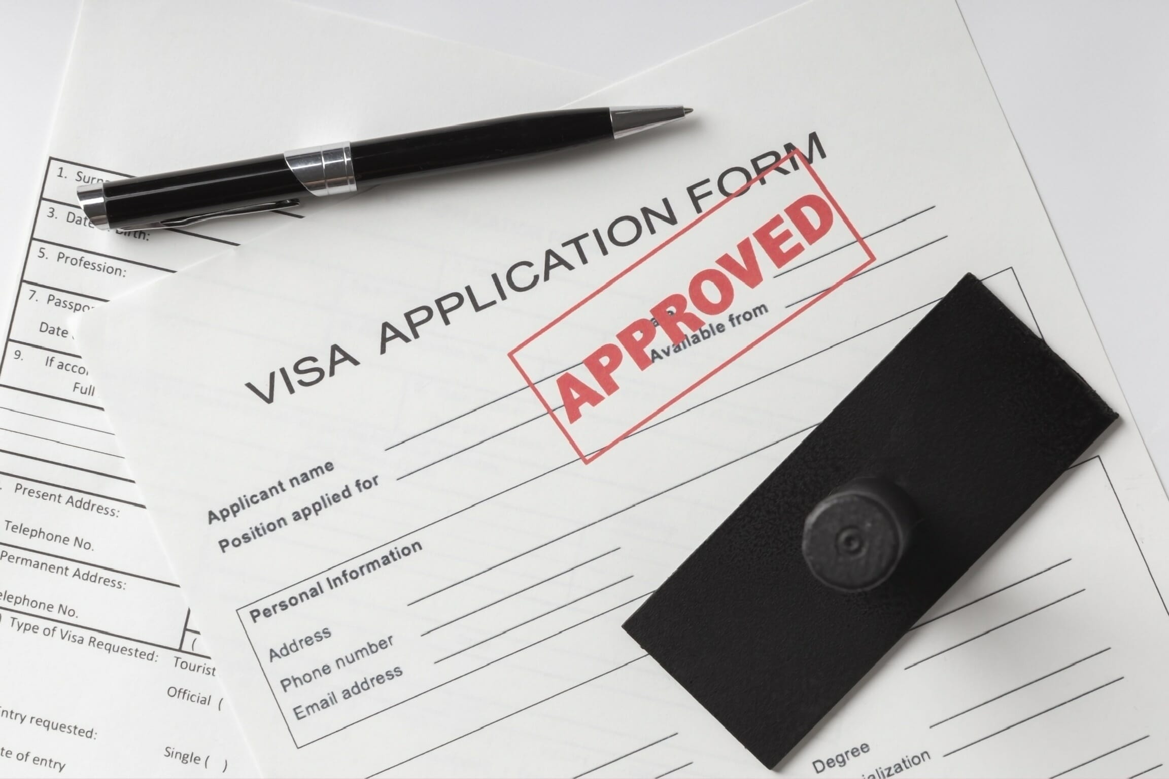 A completed visa application form with a pen and stamp