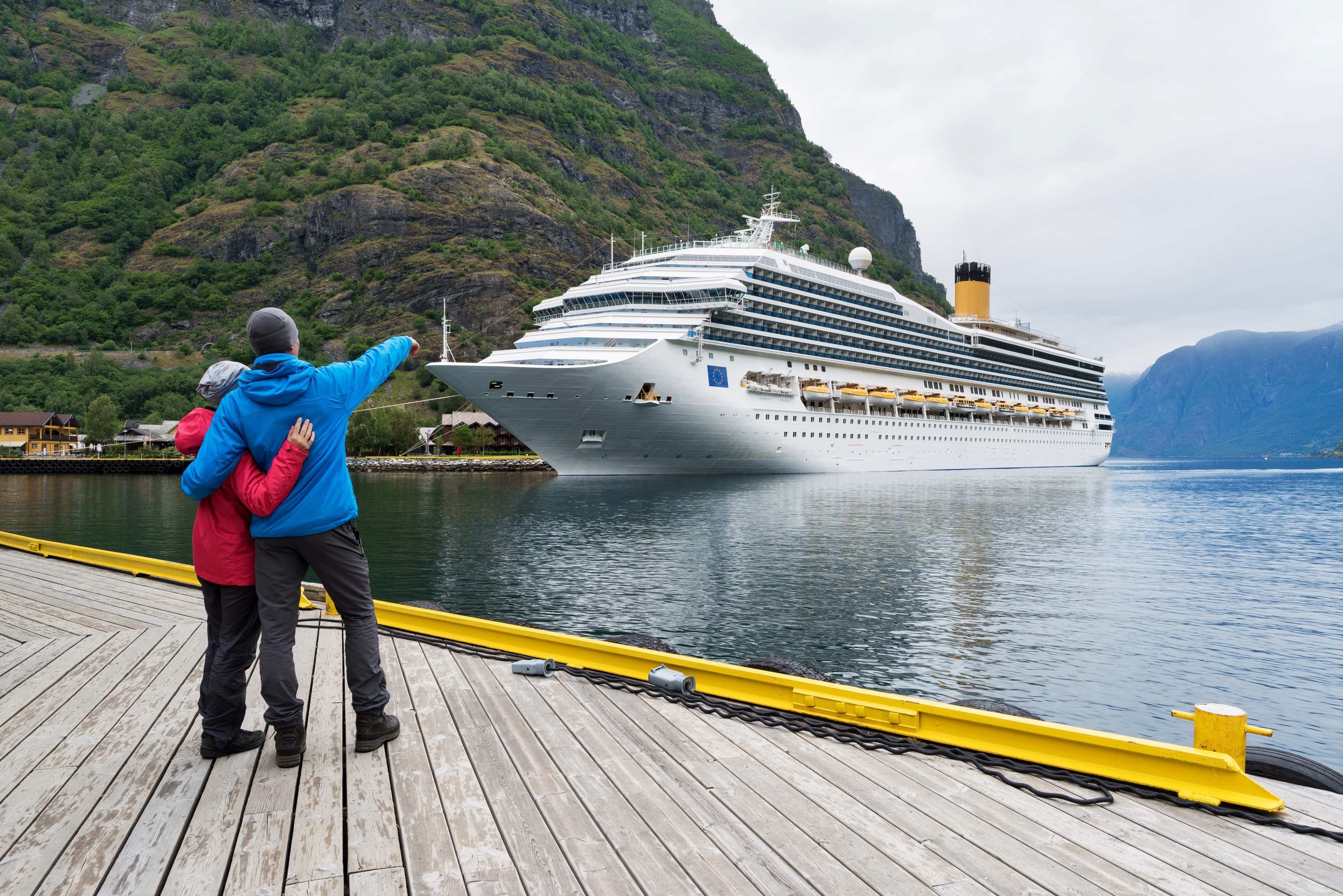 A relationship couple looking at a cruise liner in the waters of Aurlandsfjord, Norway
