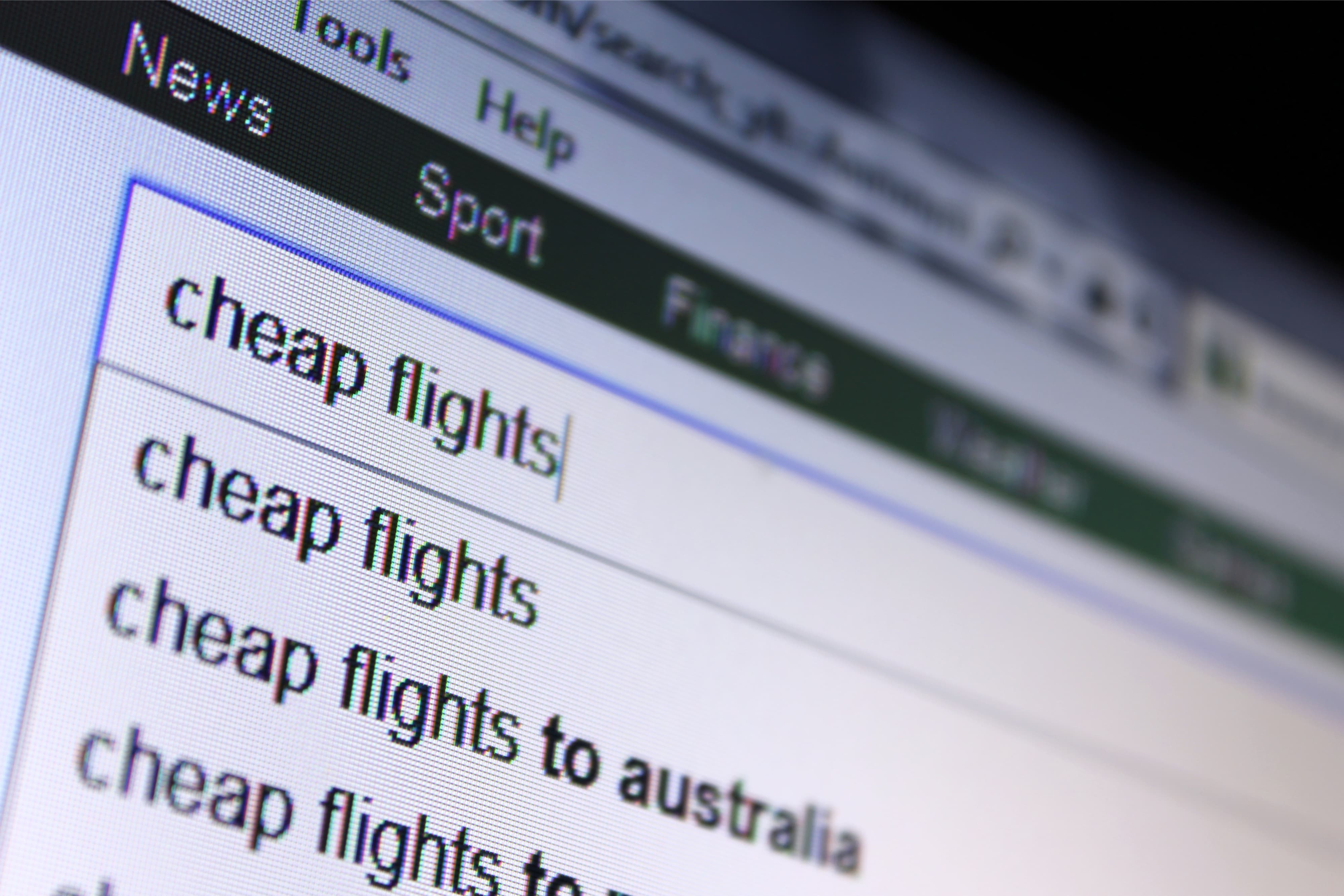 A closeup view of computer screen with text input by the computer user searching for cheap flights on internet browser search engine page