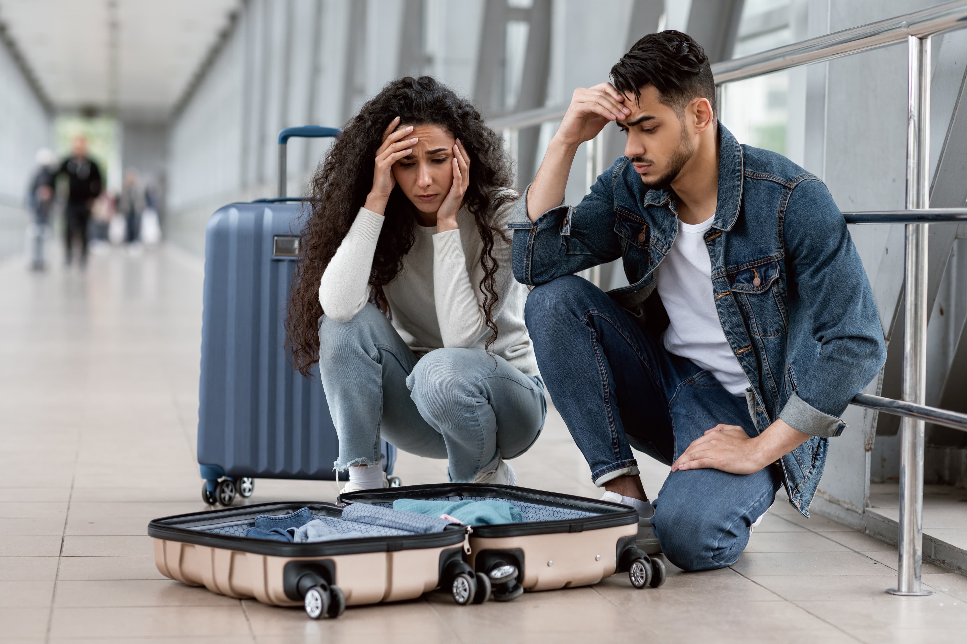 Frustrated middle eastern couple in airport looking at open suitcase for their missed items