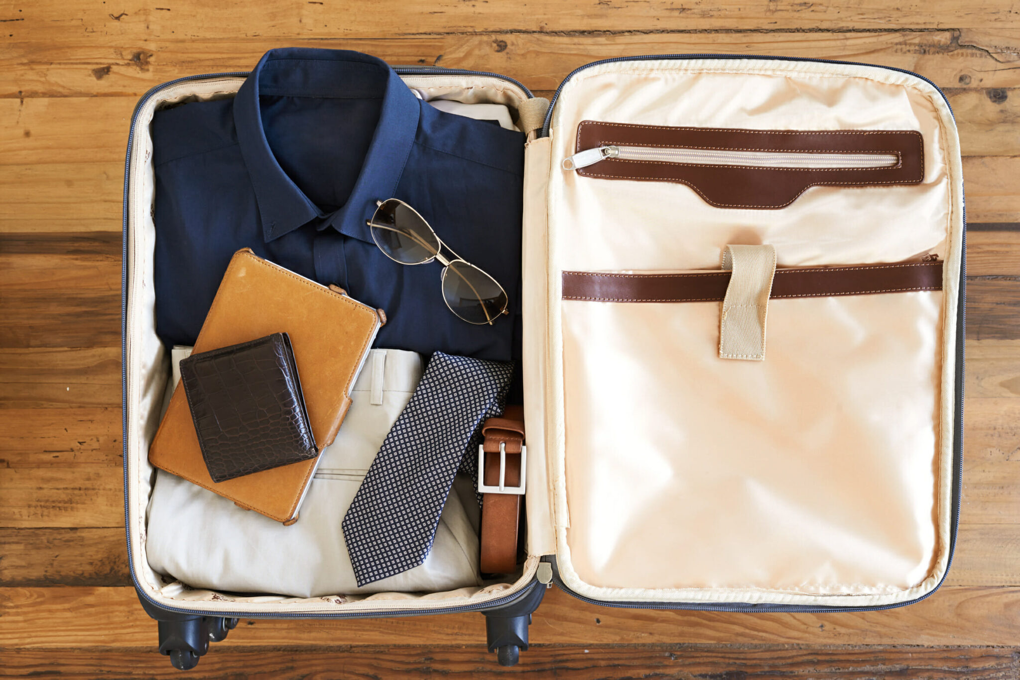 High angle shot of a suitcase packed with various essentials for a traveling businessman
