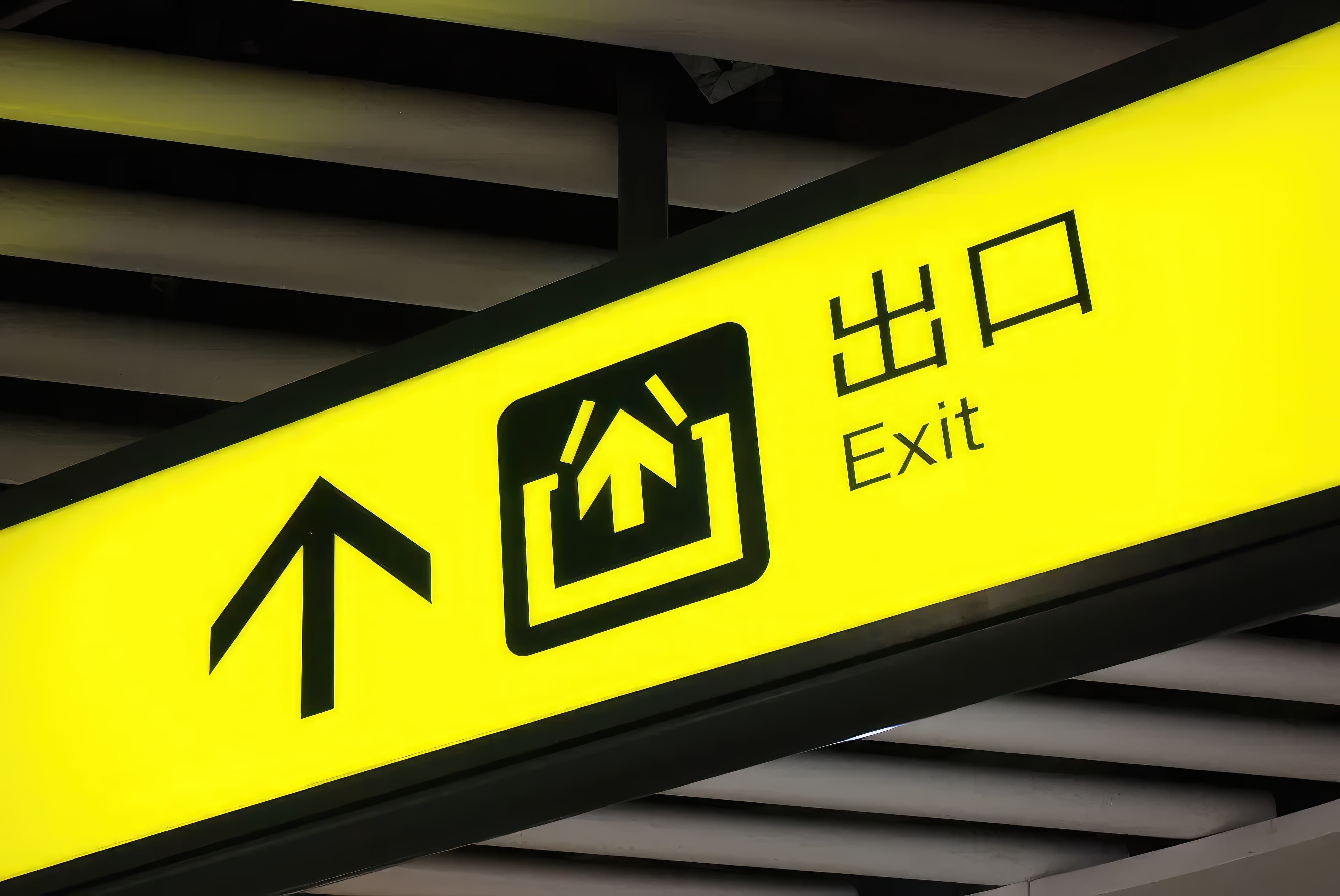 A yellow exit sign with an arrow pointing up at an airport