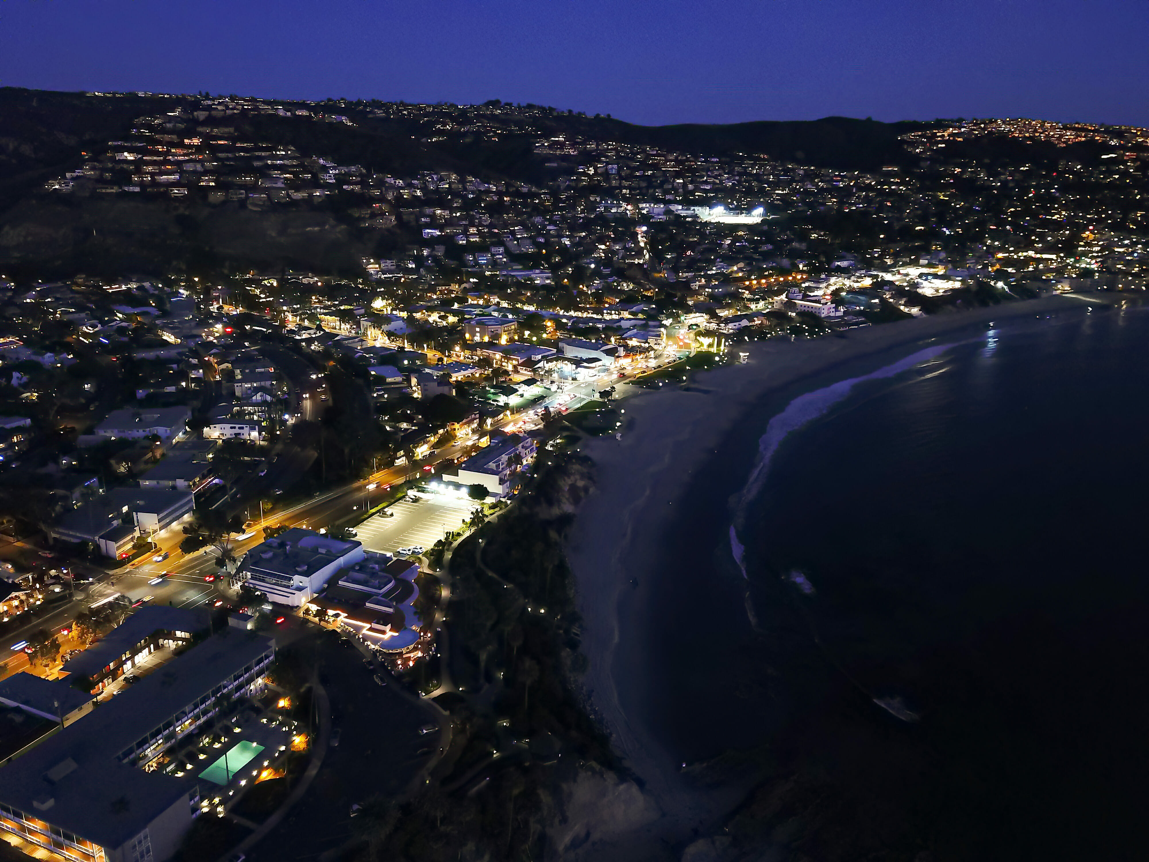 A breathtaking aerial view of the beach and city at night, showcasing the mesmerizing beauty of the illuminated coastline